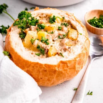 square hero image of a bread bowl filled with creamy gluten-free clam chowder.