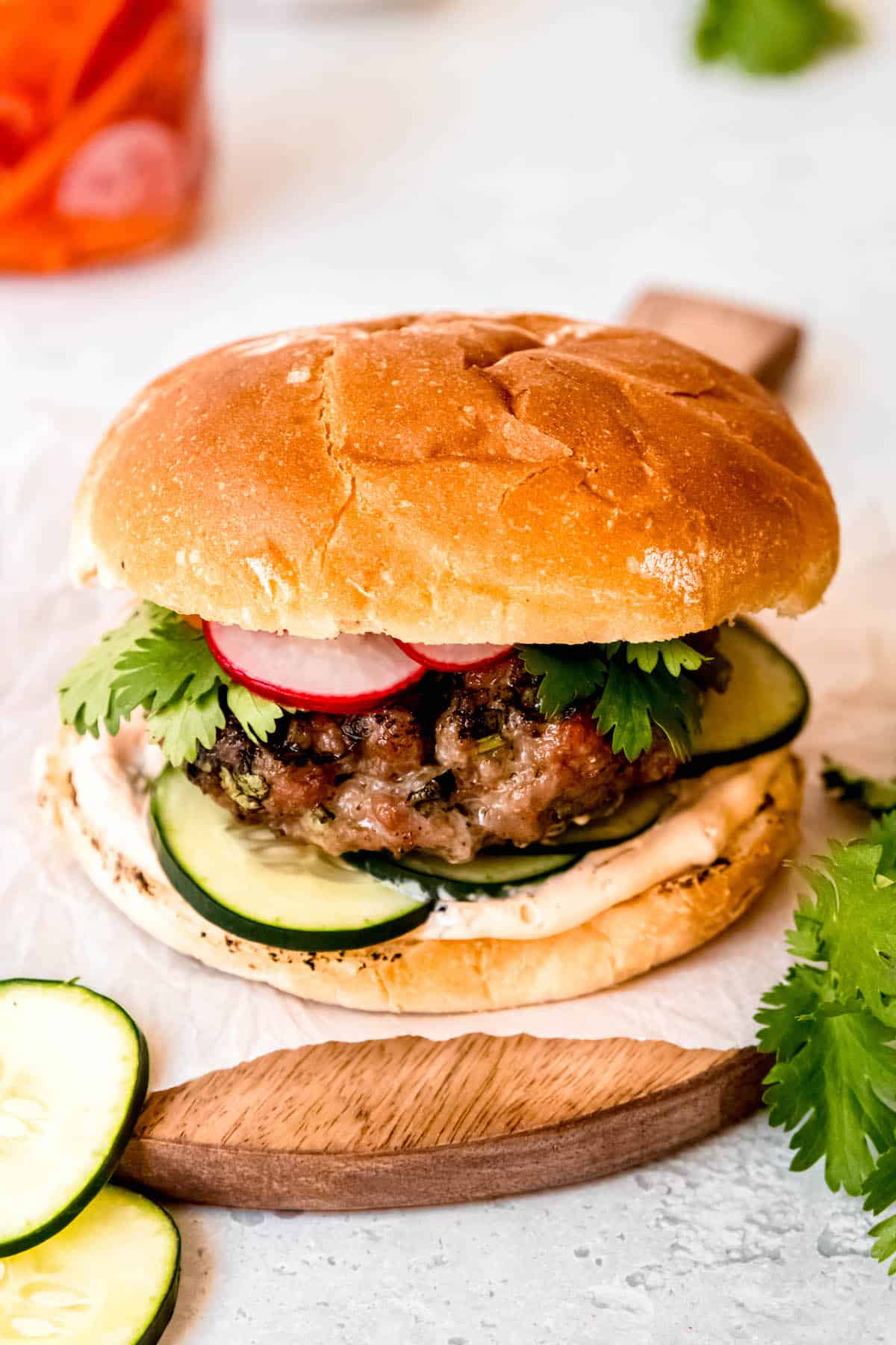 Asian pork burger atop a round wooden serving board with a handle.