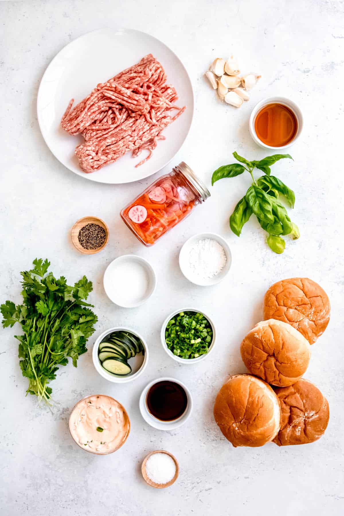 ingredients for making grilled Asian-style ground pork burgers measured out on a white table.
