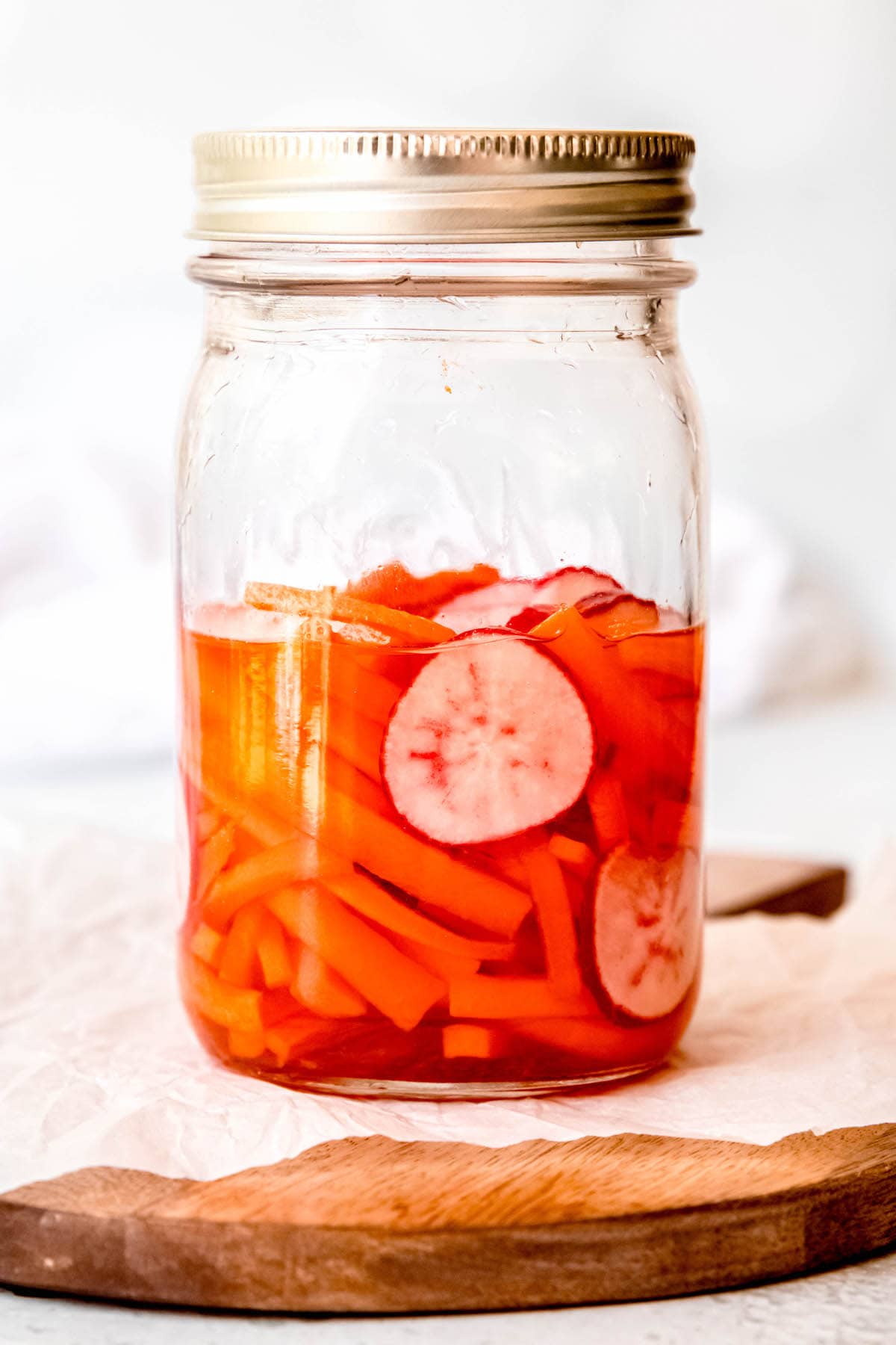 julienned carrots and thinly sliced radishes in a mason jar with banh mi-style pickling juice.