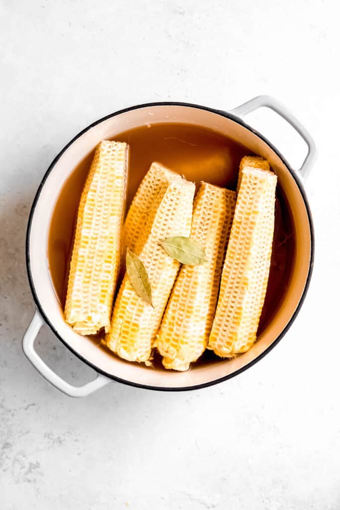 naked corn cobs added to a dutch oven with vegetable broth and two bay leaves to make corn broth for chowder.