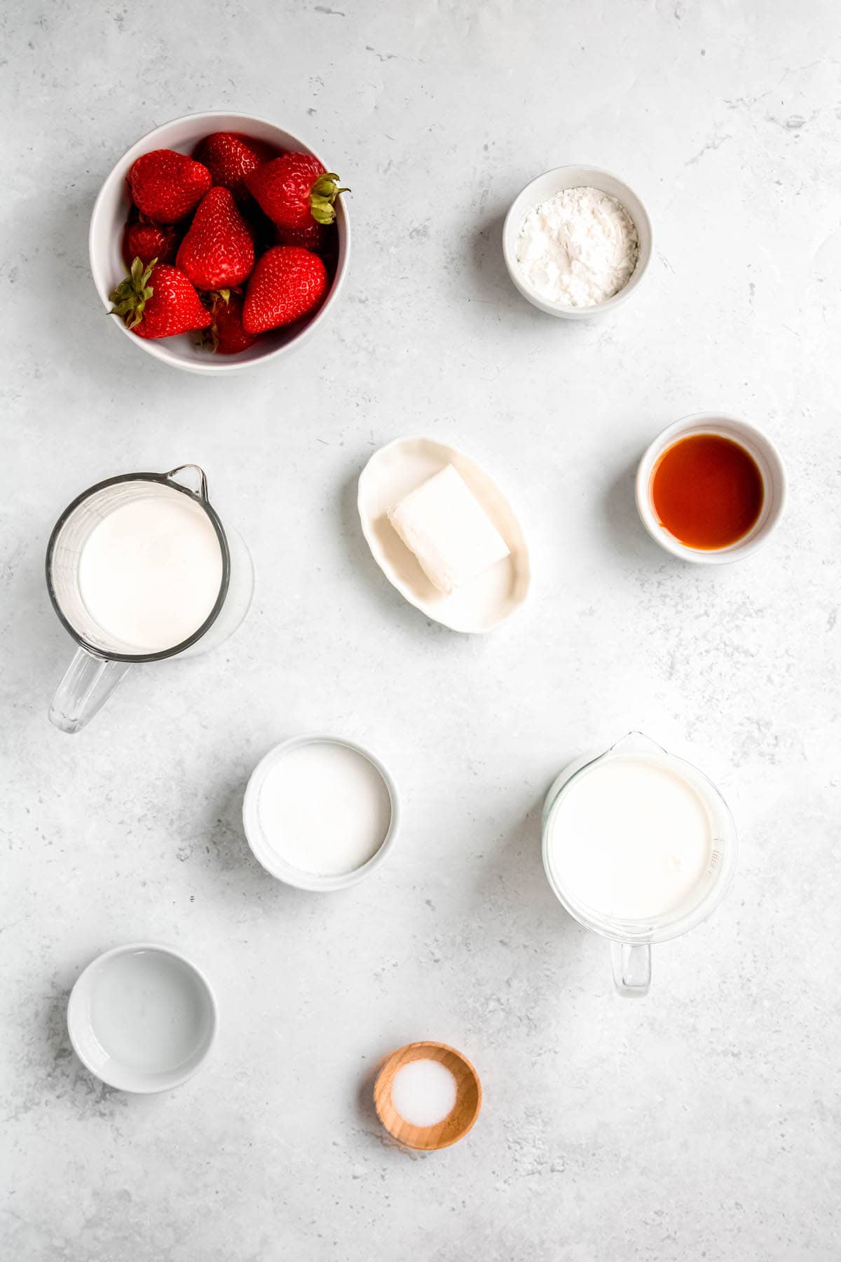 ingredients needed to make homemade strawberry swirl ice cream laid out on a white table.