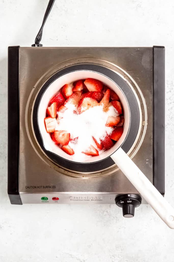 strawberries, sugar, and vanilla extract added to a saucepan.