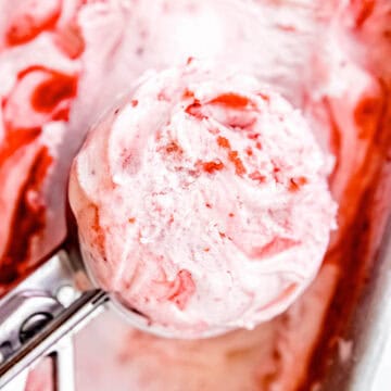 closeup shot of a scoop of vanilla and strawberry swirl ice cream.
