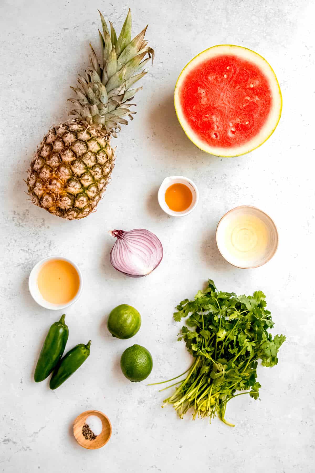 ingredients for making fresh jalapeño watermelon pineapple salad laid out on a white table.