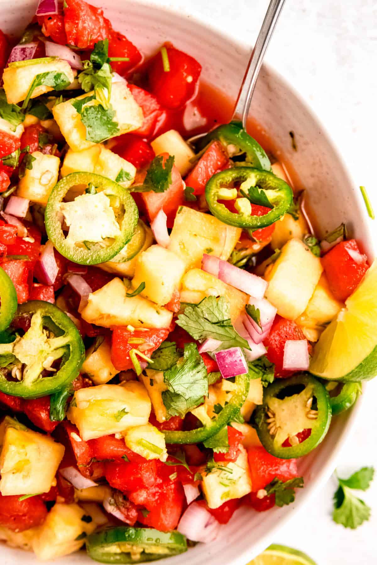 overhead shot of ½ a serving bowl of spicy watermelon salad with pineapple and jalapeño.