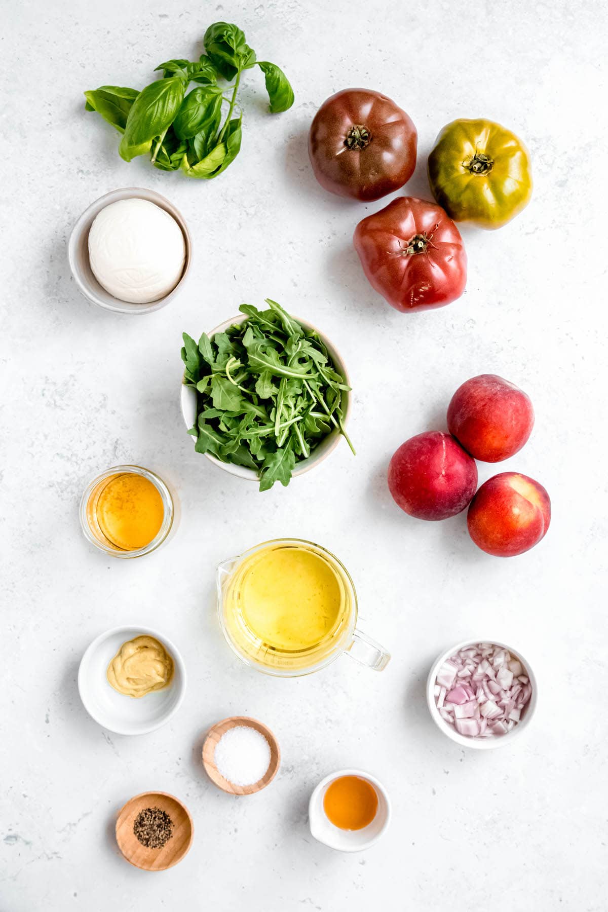 ingredients needed to make tomato burrata peach caprese salad measured out on a white table.