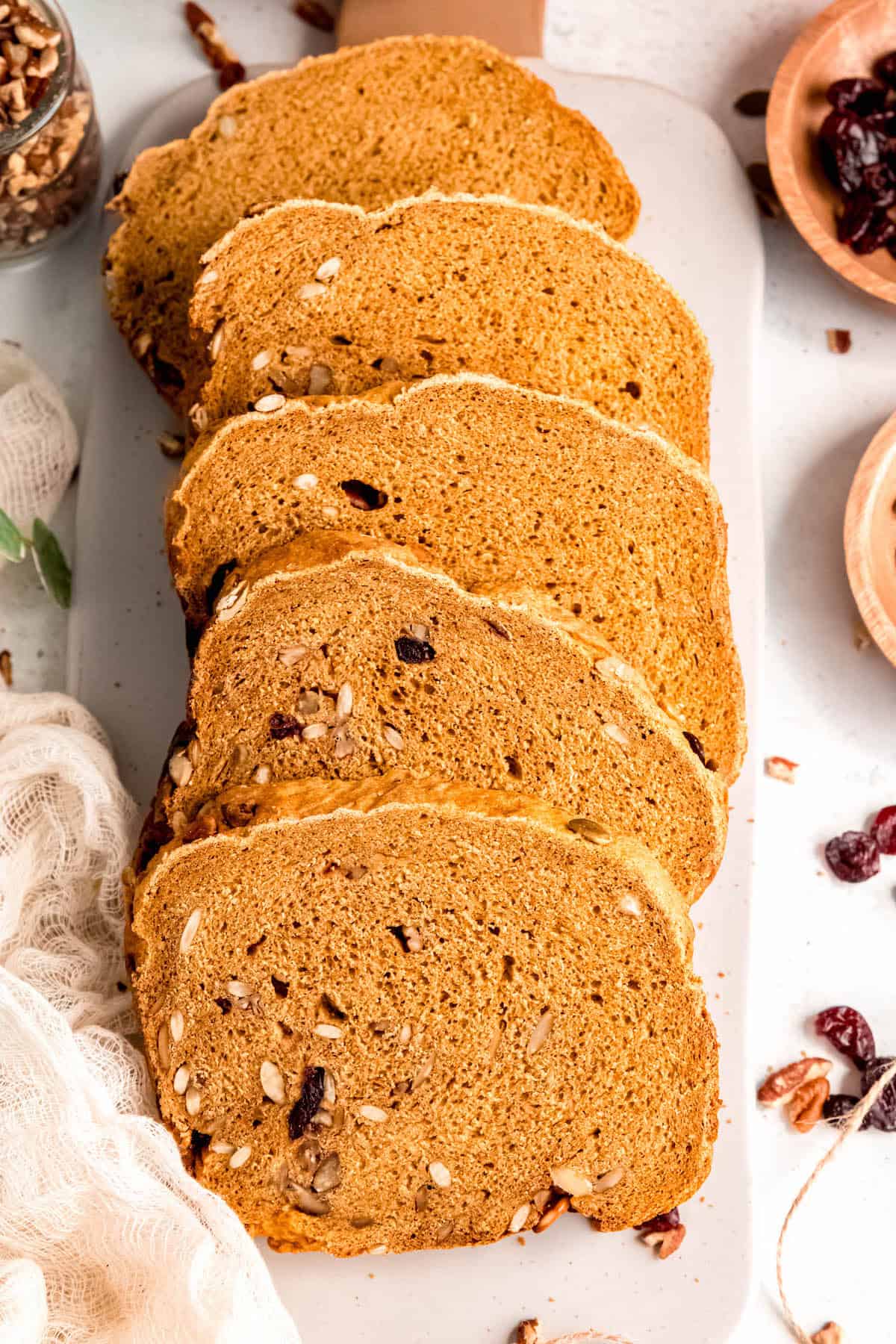 closeup shot of 5 slices of bread machine pumpkin bread on a white cutting board.