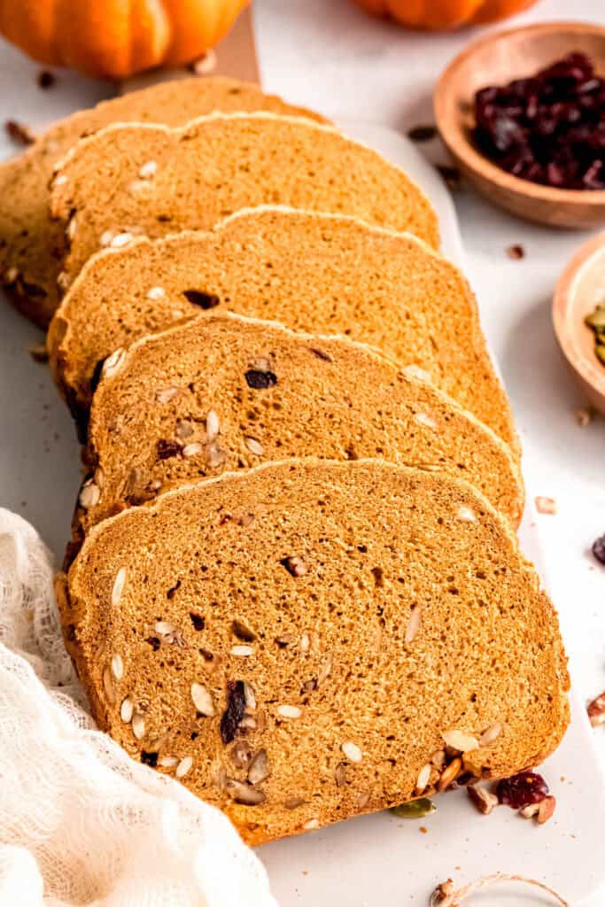 45 degree angle shot of healthy whole wheat pumpkin bread from a bread machine sliced into sandwich slices.