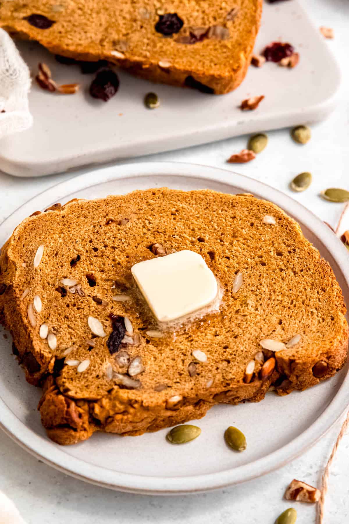 pad of butter melting on a toasted slice of cranberry pumpkin nut bread machine bread.