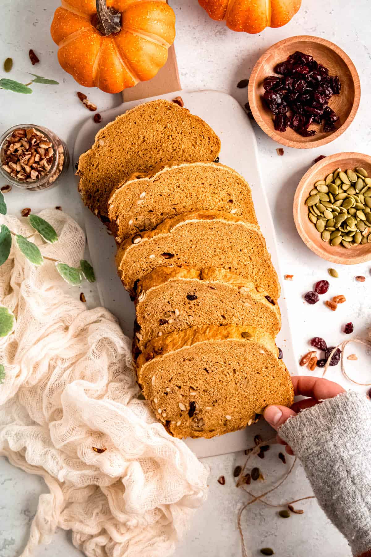 hand grabbing a slice of freshly baked pumpkin spice yeast bread made in a bread machine.