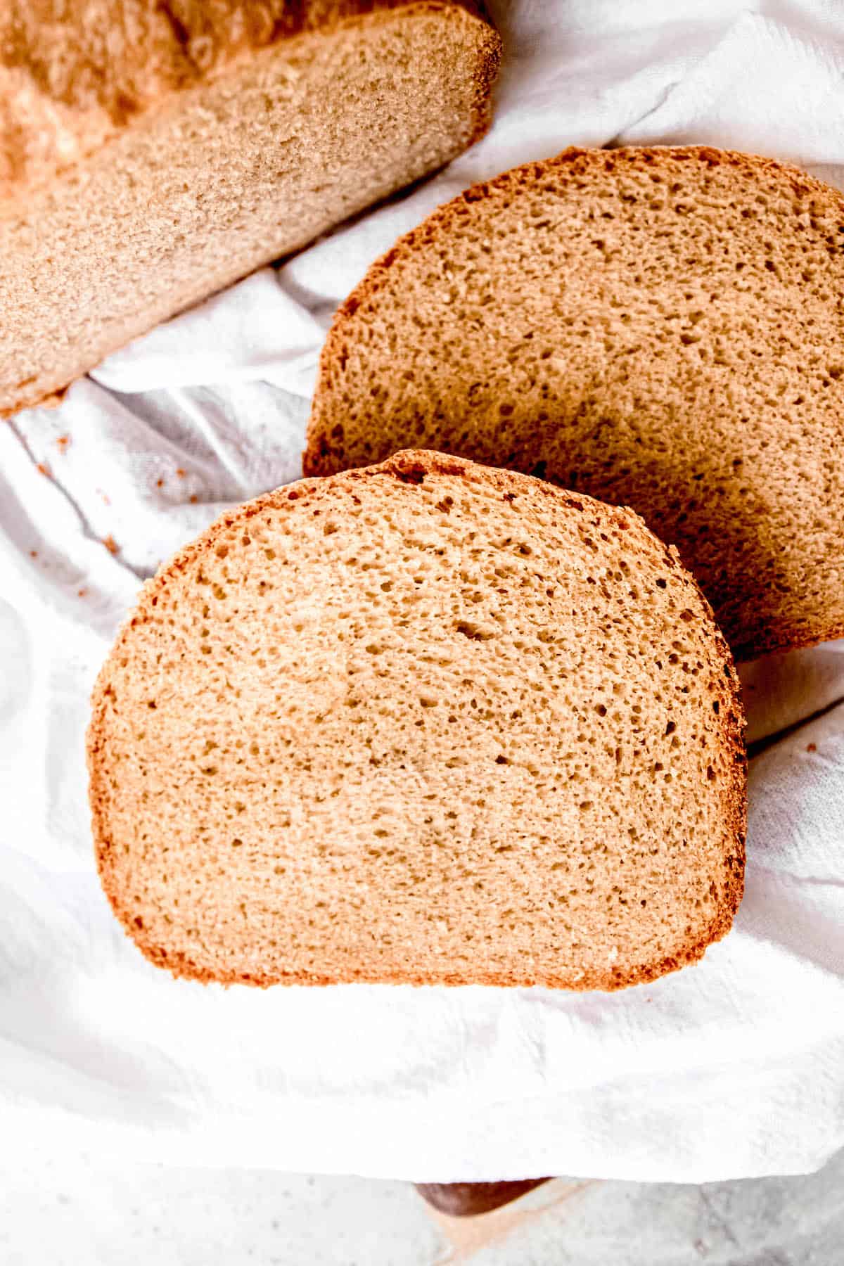 overhead shot with the butt end of the bread machine sourdough bread atop a slice with the rest of the loaf in the upper left corner.