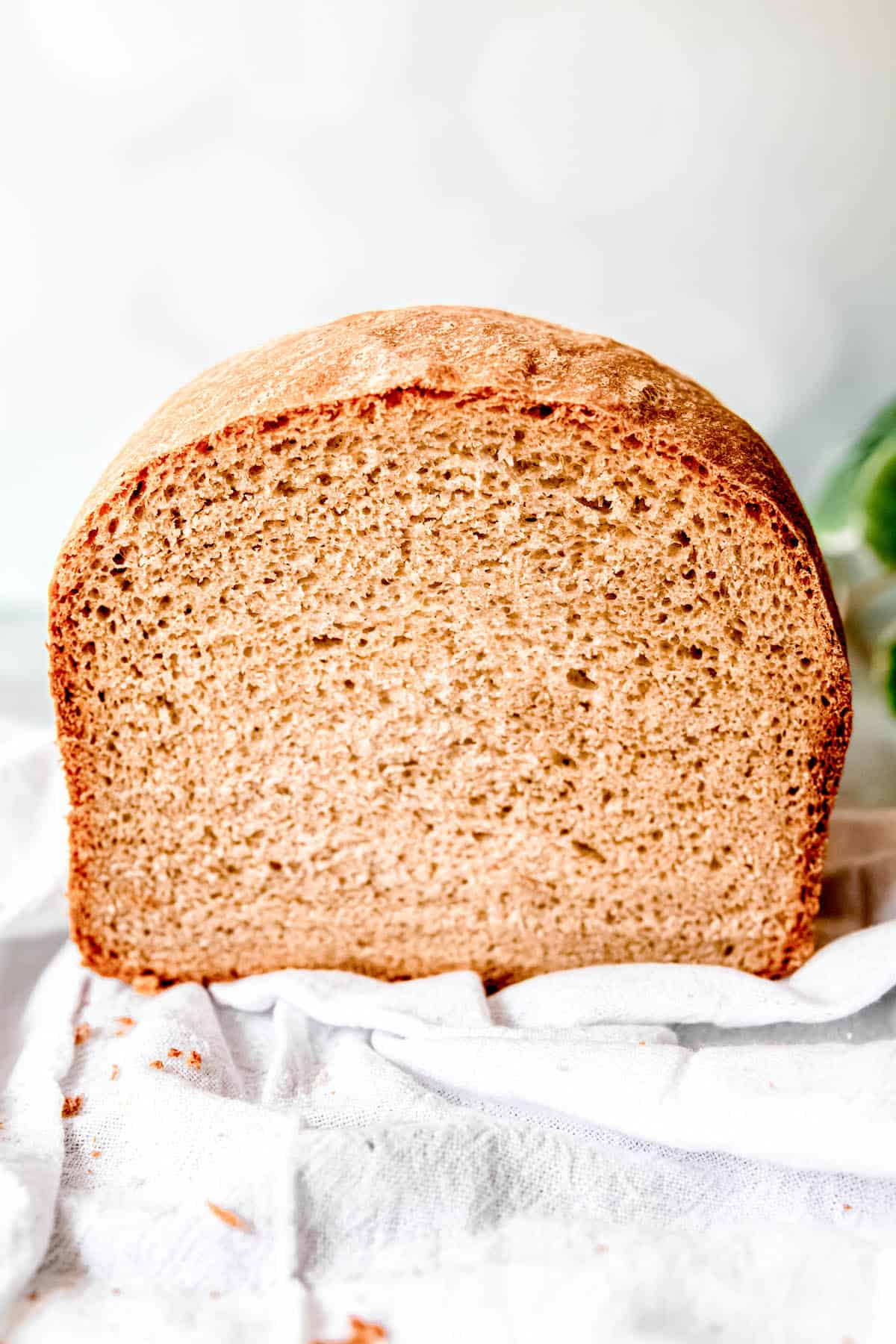 45 degree angle shot of a halved loaf of sourdough sandwich bread with a light, thin golden crust and a pale tan interior with a crumb structure that looks like store-bought bread.