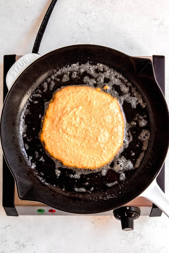 pumpkin protein pancake batter added to a skillet with butter.