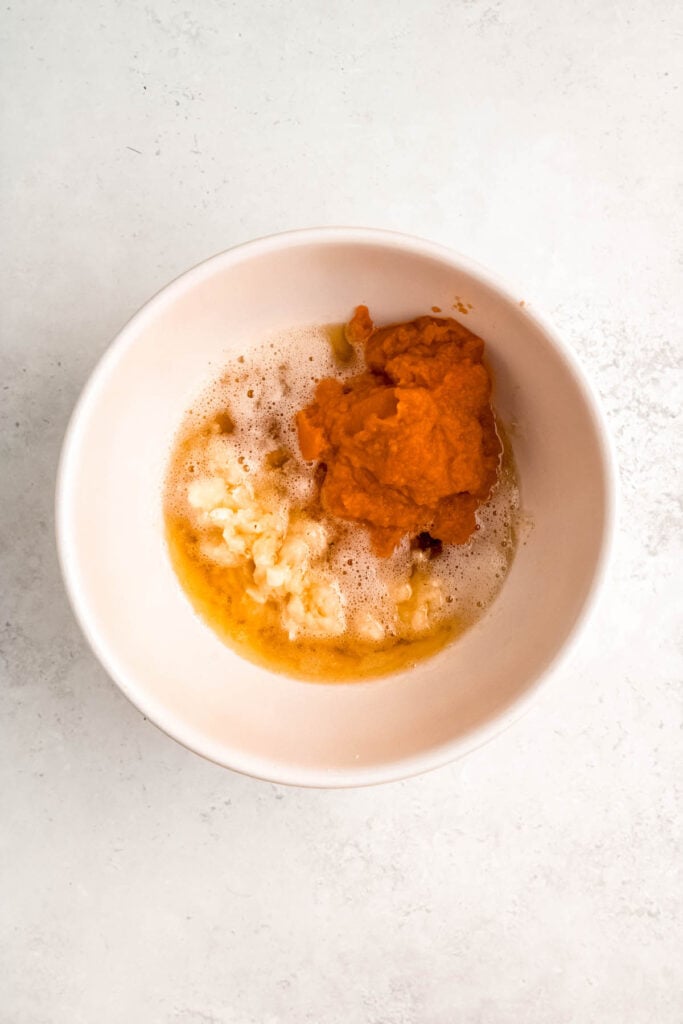 pumpkin puree and mashed banana added to a mixing bowl with the browned butter.