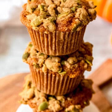 45 degree shot of a stack of 3 pumpkin and banana muffins showing off their crumbly streusel topping.