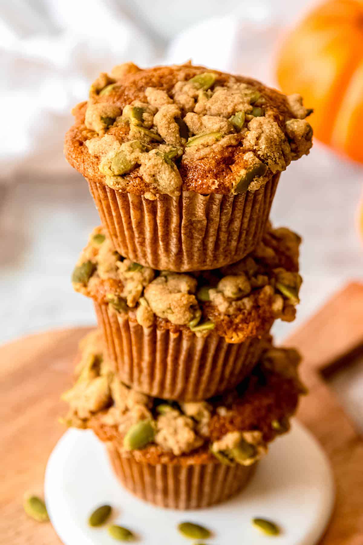 45 degree shot of a stack of 3 pumpkin and banana muffins showing off their crumbly streusel topping.