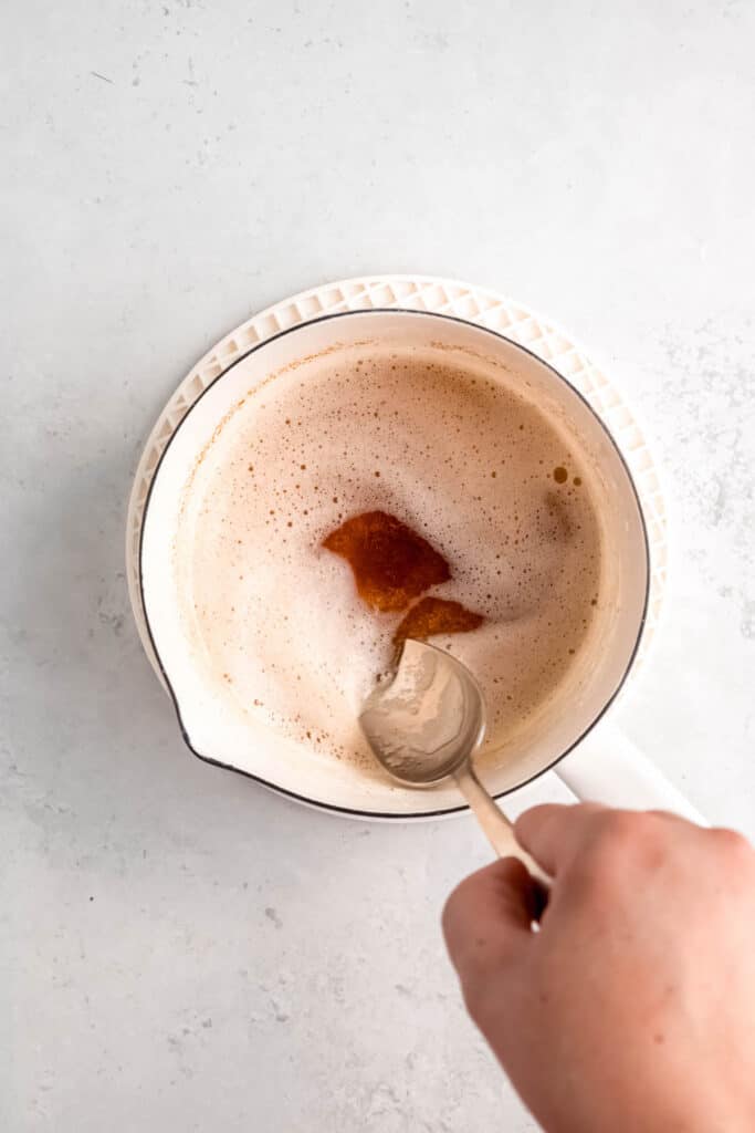 hand stirring browned butter in a small saucepan.