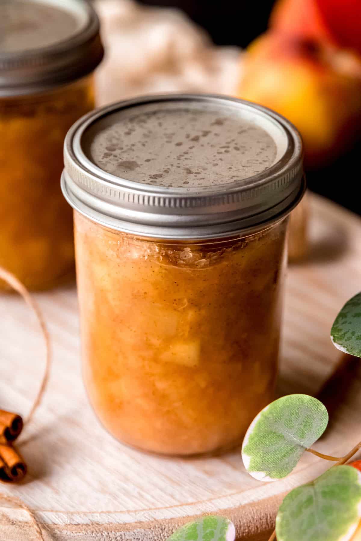 two jars of apple preserves with airtight lids speckled with water after canning.