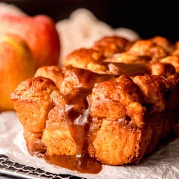 square closeup on the side view of cinnamon apple monkey bread drizzled with spiced salted caramel maple sauce before being pulled apart.