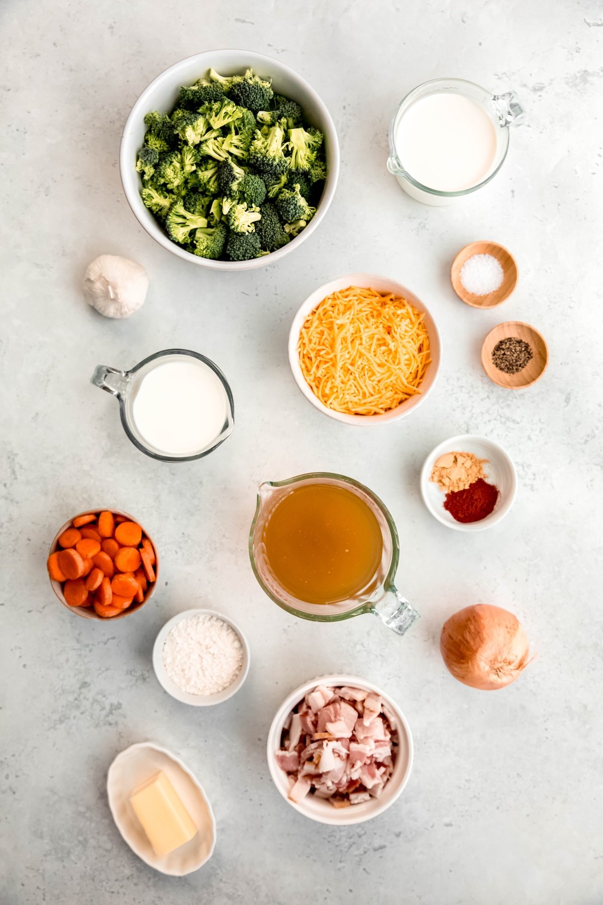 ingredients measured out to make bacon broccoli cheddar soup like Panera Bread in white bowls on a white table.