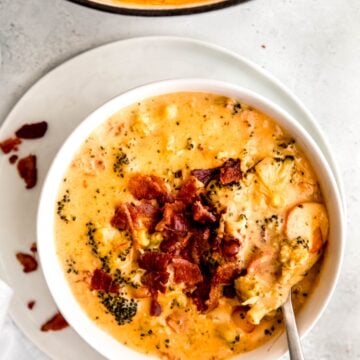 hand taking a bite of copycat panera bacon broccoli cheddar soup with a silver spoon.