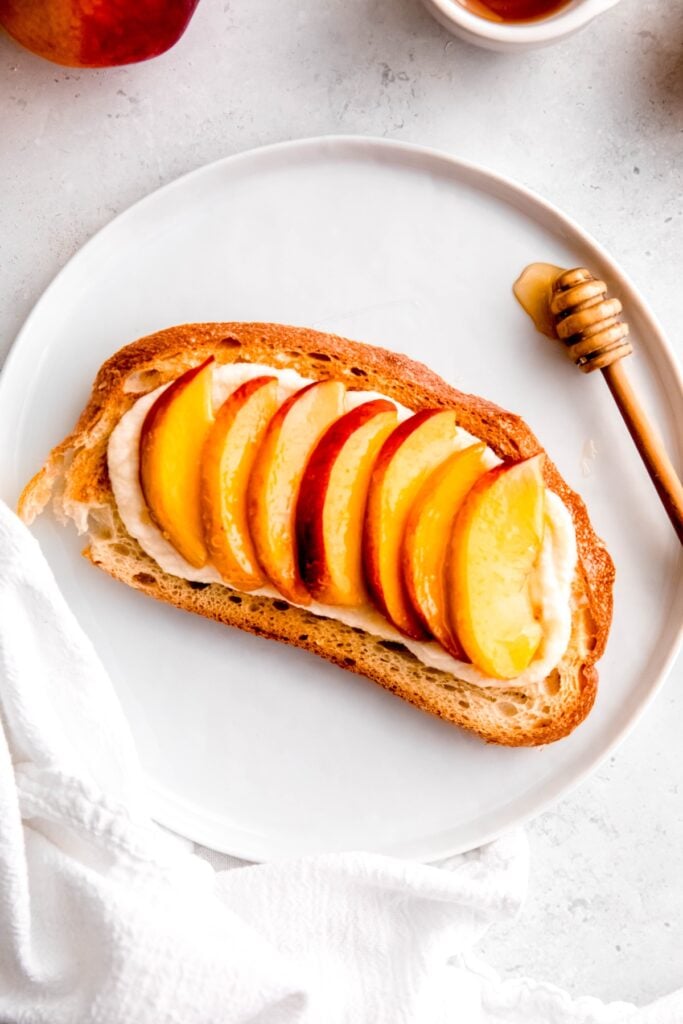 closeup overhead shot of peaches and honey breakfast toast with ricotta.