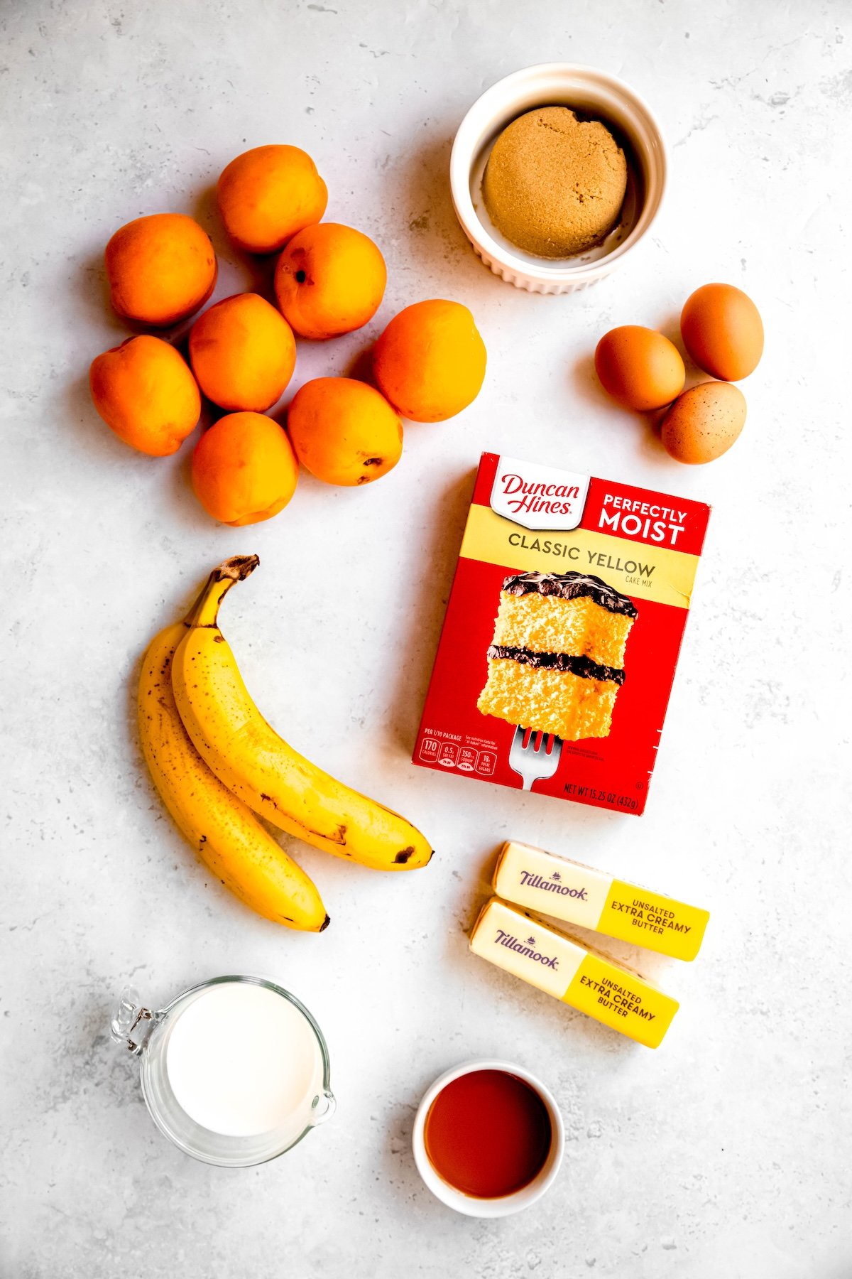 ingredients for making almond, apricot and banana upside-down cake recipe measured out on a white table.