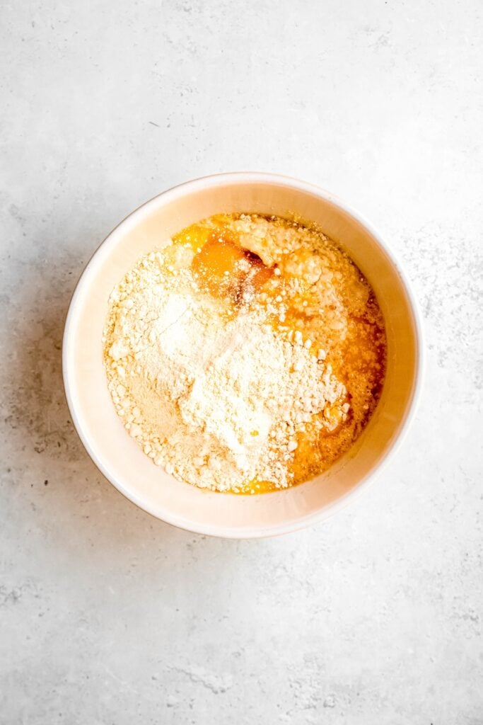 yellow cake mix, amaretto, eggs, milk, and melted butter added to a mixing bowl.