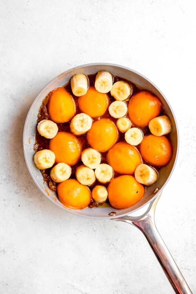 sliced bananas and halved apricots added to the skillet with the caramel; they're packed in tightly so there's not many gaps showing the caramel underneath.
