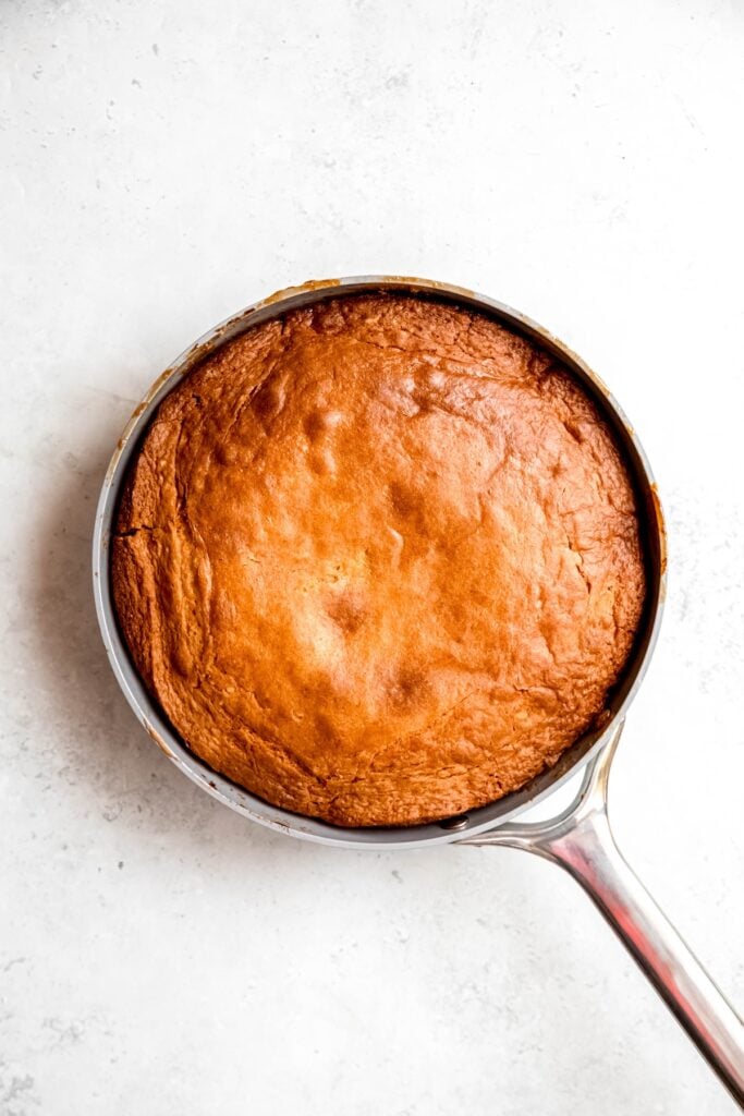 skillet with the baked apricot banana upside down cake before inverting it onto a serving platter; the edges are deep golden-brown.