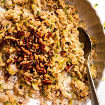right three quarters of a white bowl filled with zucchini banana bread oatmeal.