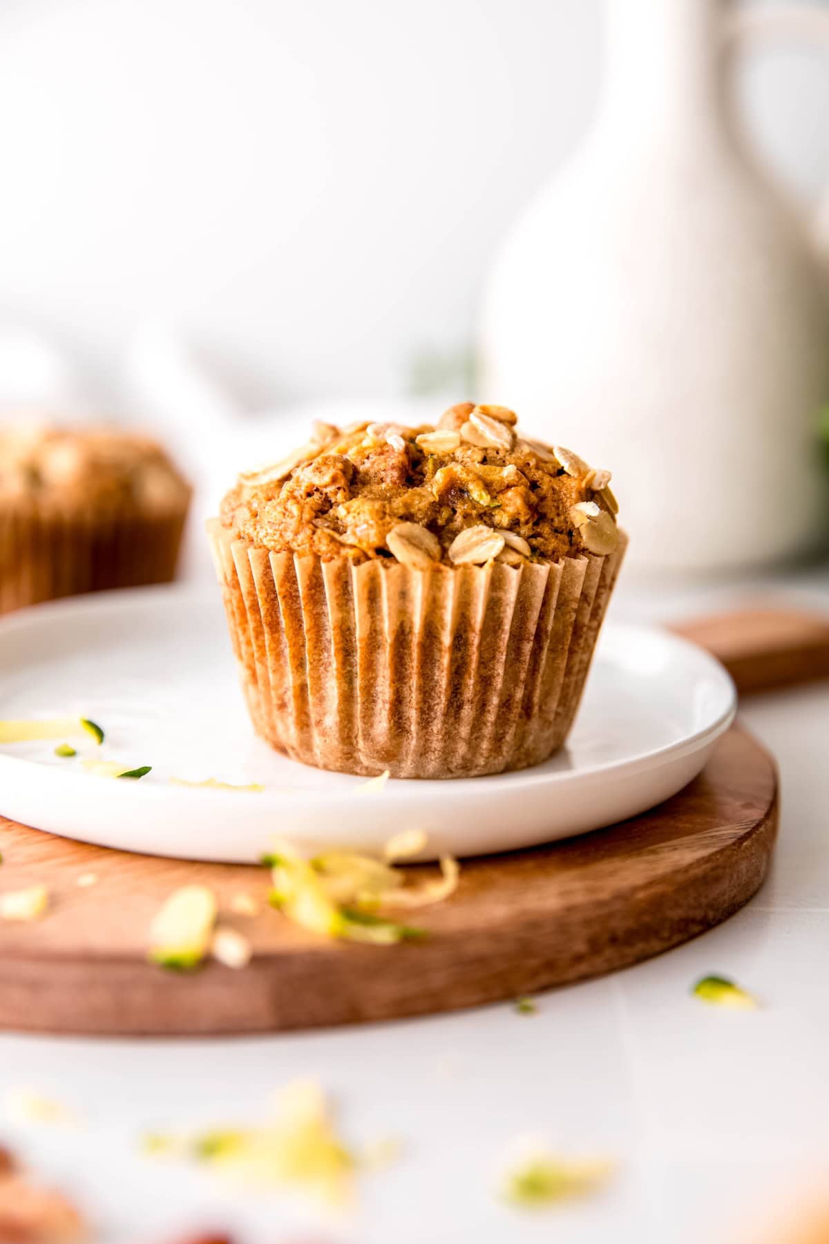 healthy vegan zucchini muffin on a white plate topped with rolled oats.