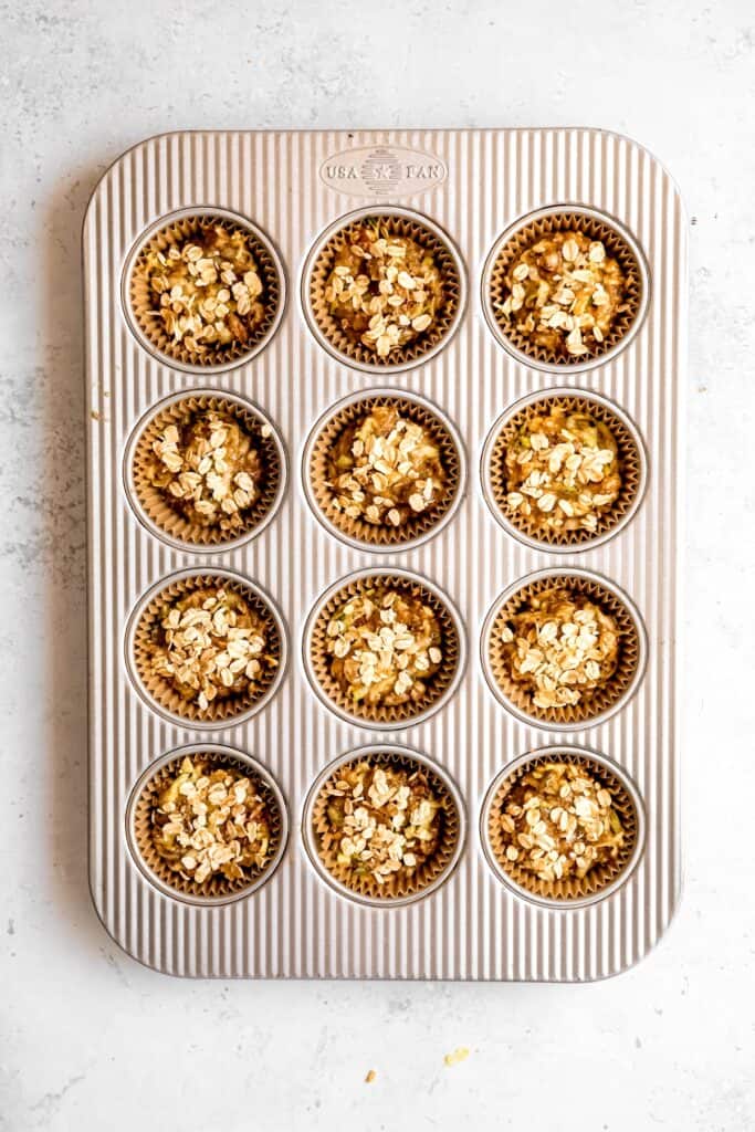 raw vegan zucchini muffins sprinkled with rolled oats and turbinado sugar before baking.