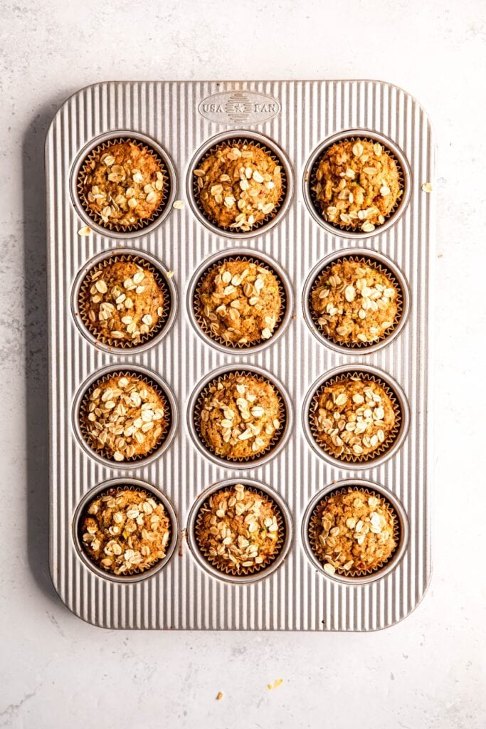baked vegan zucchini muffins cooling in the baking tin before removing to a wire rack.