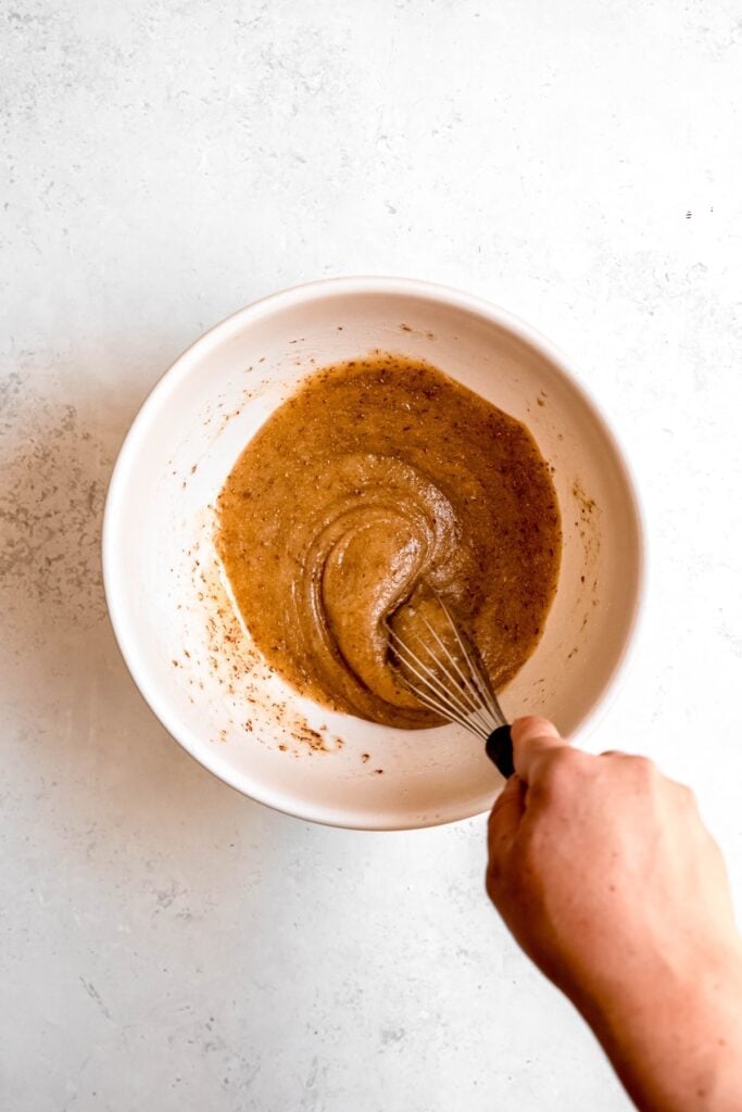 action shot of a hand whisking the flax vegan eggs with the oil and sugars.
