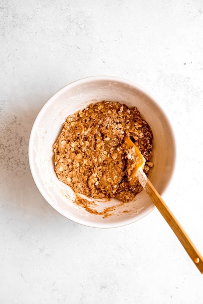 muffin batter after adding the dry ingredients; it looks dry and craggy with a few streaks of dry ingredients.