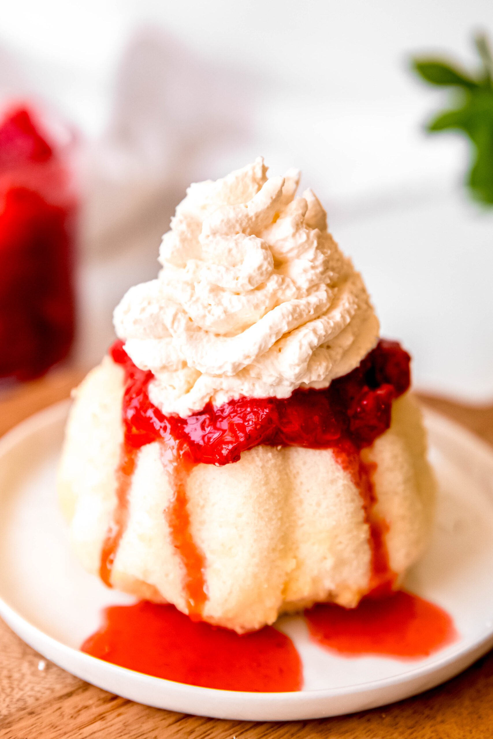 classic whipped cream atop a strawberry shortcake with strawberry juices running down onto the plate.