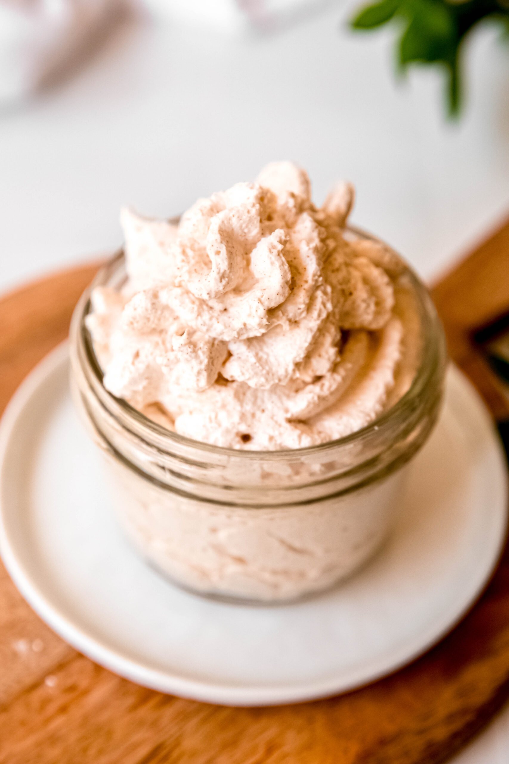45 degree angle downward shot of prettily piped cinnamon whipped cream in a small mason jar.