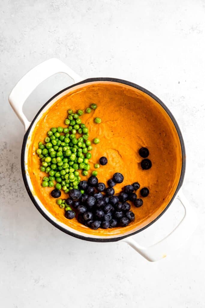 blueberries and peas added to the blended rice, pumpkin, and chicken mixture in the pot.