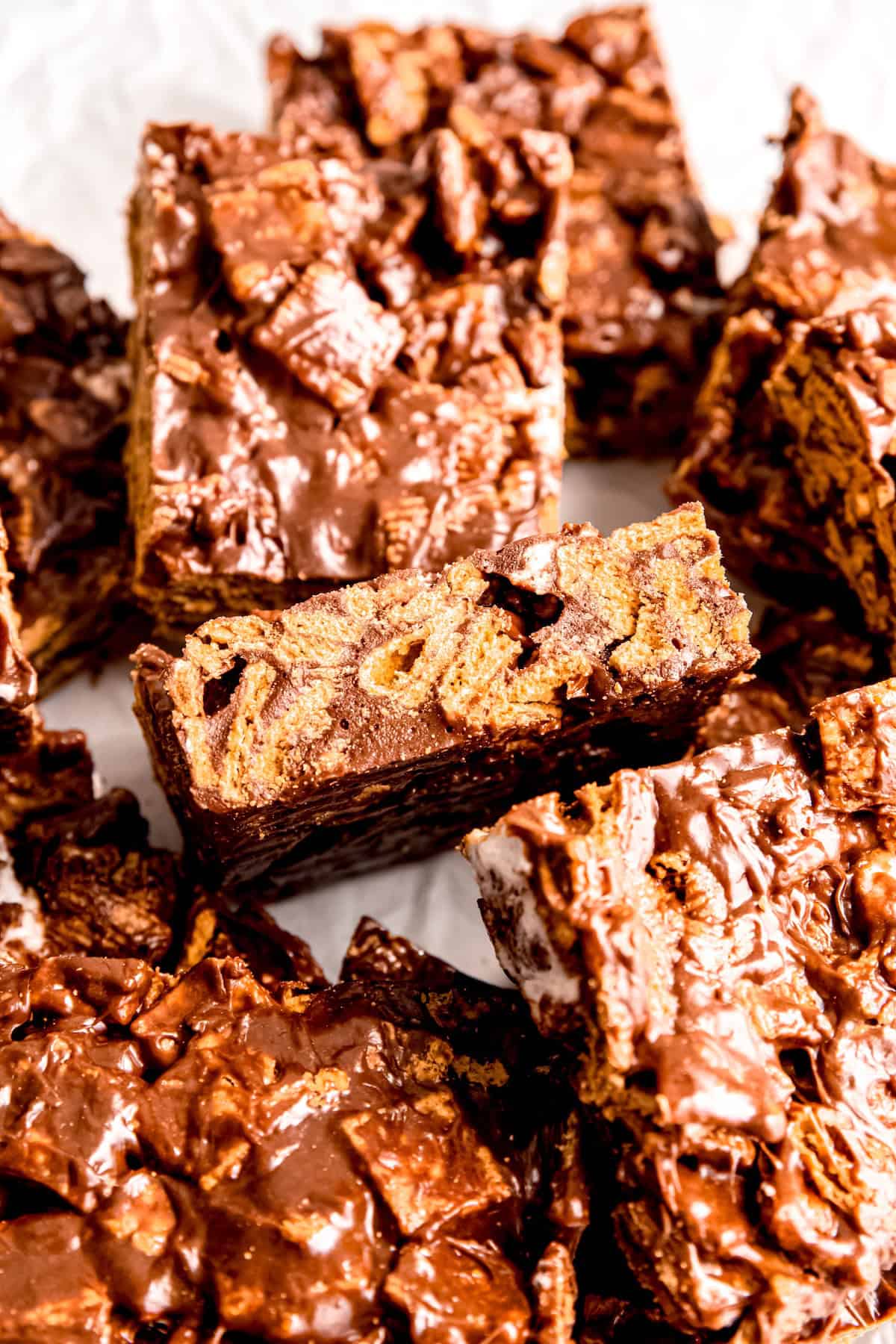 pile of indoor s'more bars with one turned sideways to show the crunchy grahams and sticky marshmallows encased in chocolate.