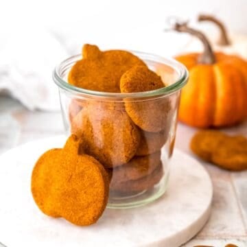 jar of 4 ingredient peanut butter pumpkin oatmeal dog treats on a white table.