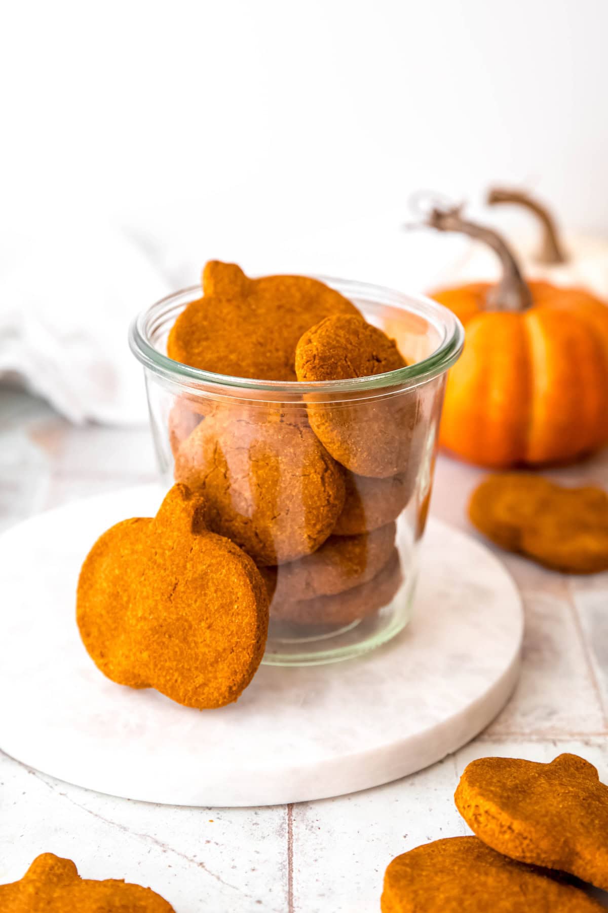 jar of 4 ingredient peanut butter pumpkin oatmeal dog treats on a white table.
