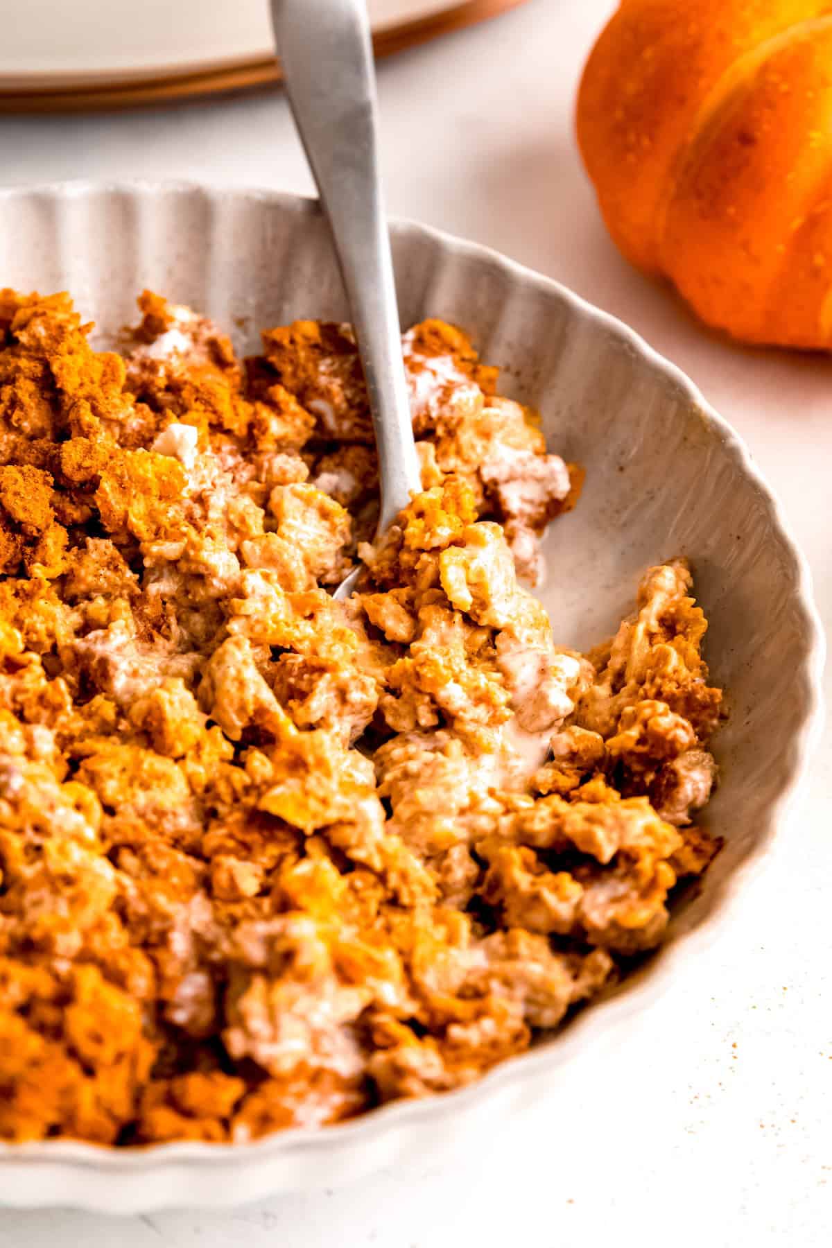 right half of a bowl of baked pumpkin pie oatmeal with a silver spoon taking a bite out.