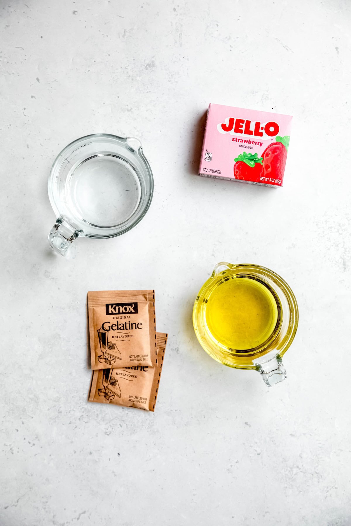 ingredients for making homemade cannabis infused weed gummies measured out on a white table.