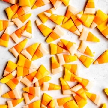square overhead shot of a jumble of homemade honey candy corn on a white table.