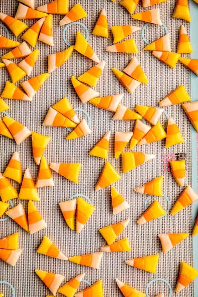 honey candy corn pieces on a silicone mat on a baking sheet after cutting into triangles.