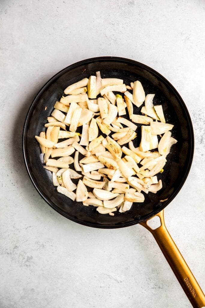 raw sliced fennel added to a saute pan with oil.