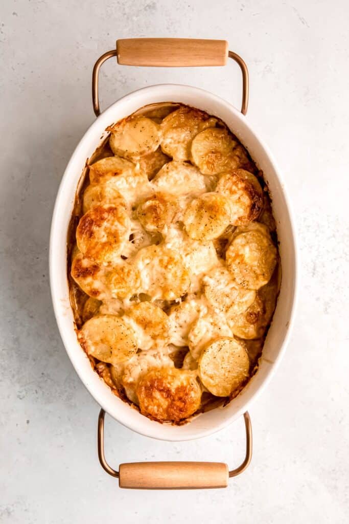 baked potato gratin with caramelized fennel cooling on a white table.