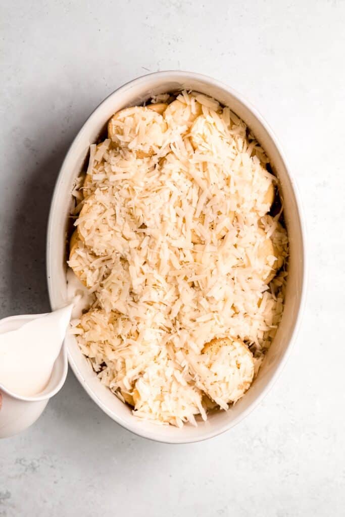 action shot of cream being drizzled over the potato fennel gratin.